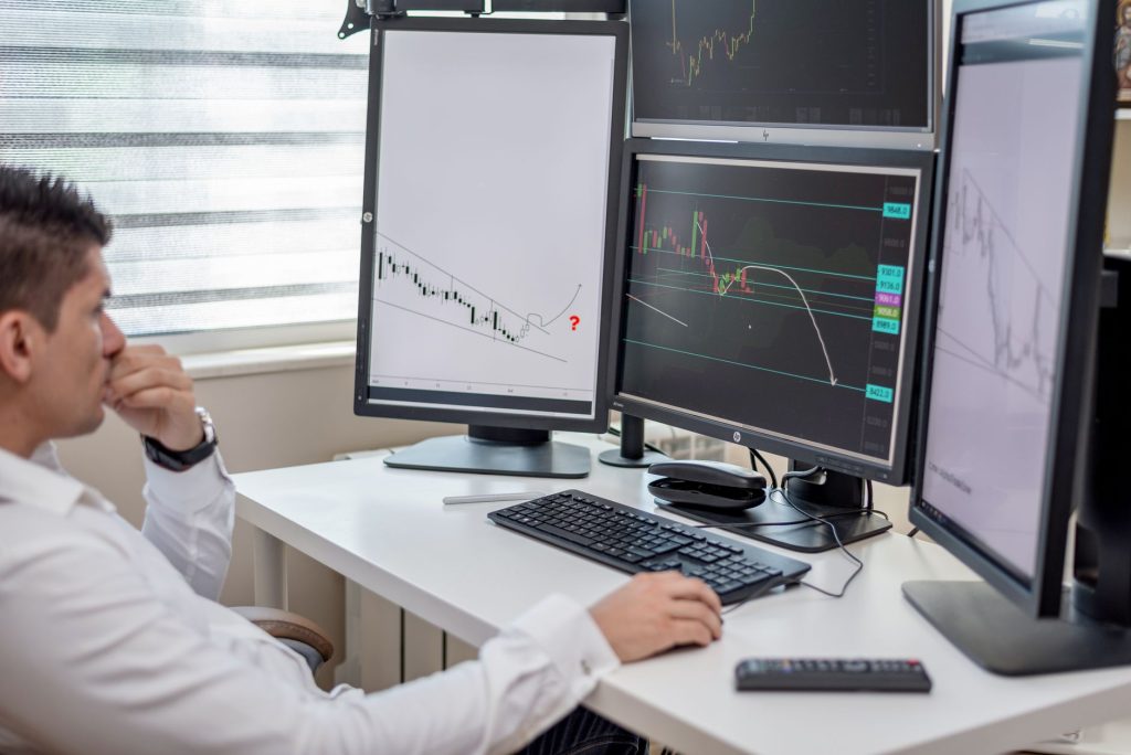 An analyst reviews multiple screens displaying different cloud billing dashboards, highlighting the challenge of fragmented multi-cloud cost visibility.