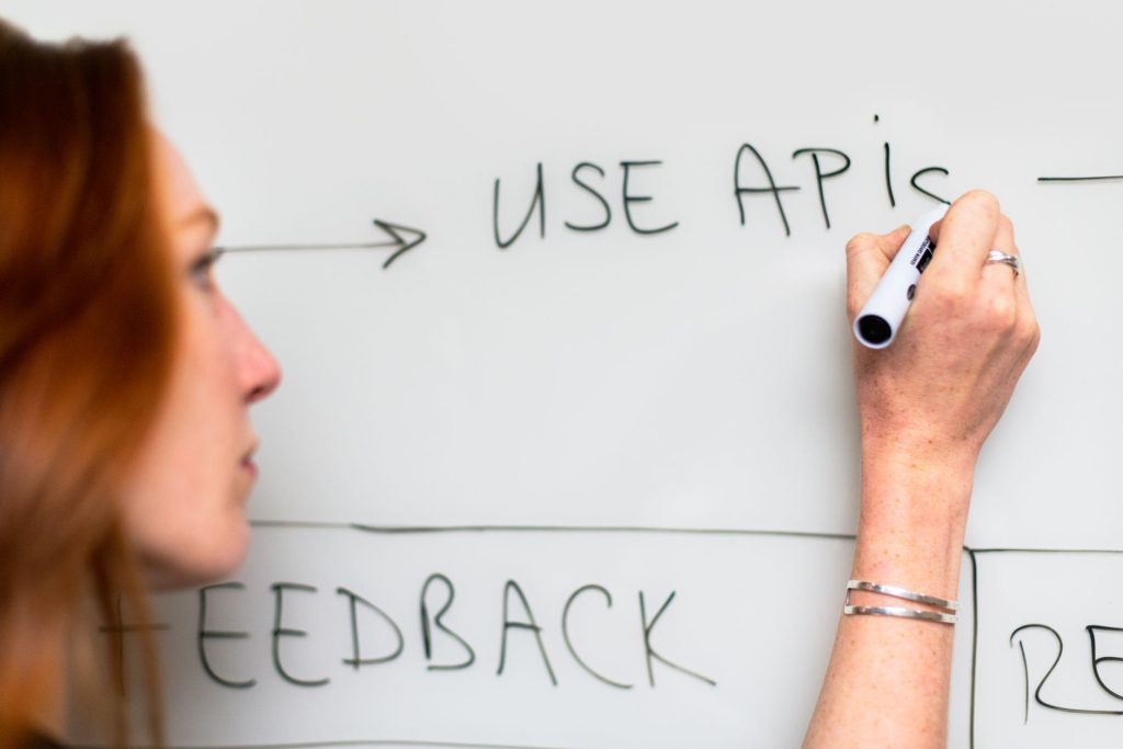 A modern office setting where software engineers review system architecture and delivery models on a digital whiteboard.