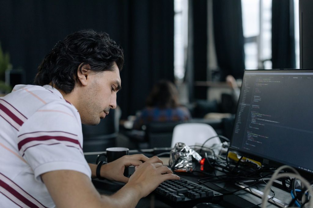 An engineer sitting with a client in a modern office, debugging integration code on a laptop screen.