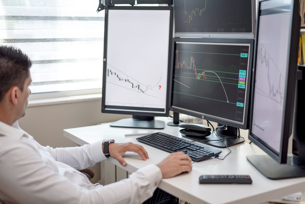 Two financial analysts reviewing automated AML scenarios and risk alerts on large office monitors.